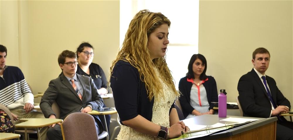 Student standing at a podium presenting to class